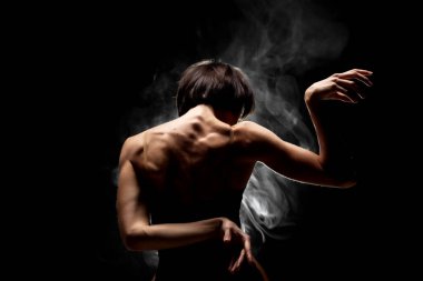 Yarı siluet modern balerin esmer arka planda dumanla poz veriyor.