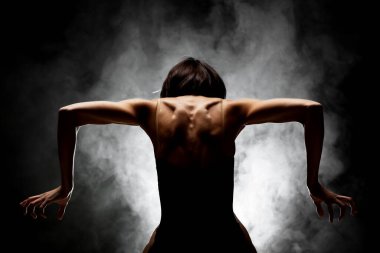 Yarı siluet modern balerin esmer arka planda dumanla poz veriyor.