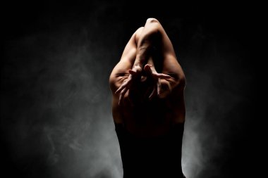 Yarı siluet modern balerin esmer arka planda dumanla poz veriyor.