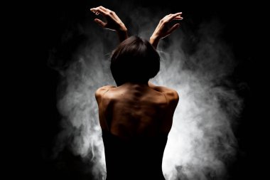 Yarı siluet modern balerin esmer arka planda dumanla poz veriyor.