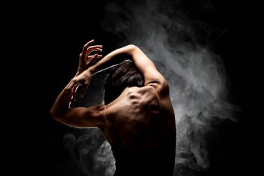 Yarı siluet modern balerin esmer arka planda dumanla poz veriyor.