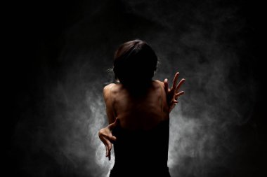 Yarı siluet modern balerin esmer arka planda dumanla poz veriyor.