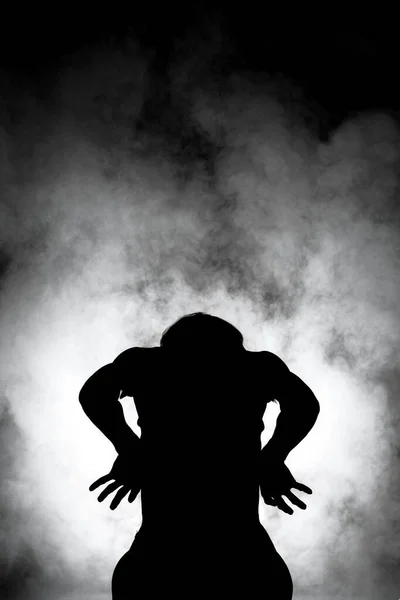 silhouette modern ballet dancer posing on dark background with smoke