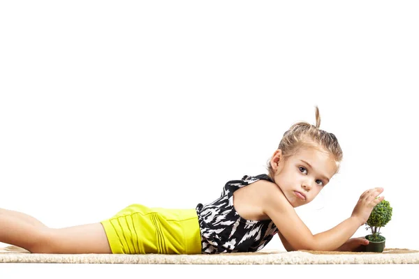 かわいい女の子が地面に横たわって小さなおもちゃの木で遊んでいます — ストック写真