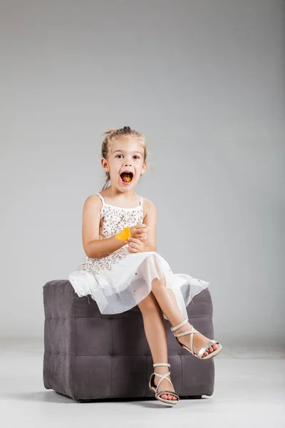 Ευτυχισμένο Κοριτσάκι Που Κάθεται Ένα Σκαμνί Στο Στούντιο Τρώγοντας Πατατάκια — Φωτογραφία Αρχείου