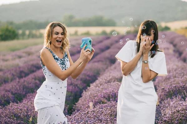 Zwei Frauen Amüsieren Sich Auf Blumenfeld Mit Seifenblasen — Stockfoto