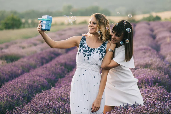 Zwei Frauen Amüsieren Sich Auf Blumenfeld Mit Seifenblasen — Stockfoto
