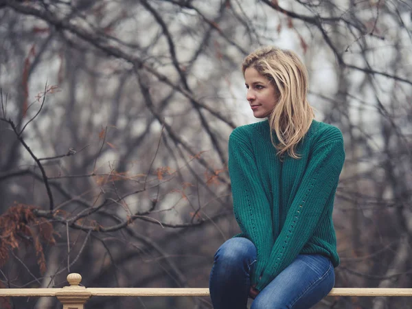 公園のフェンスの上に座って孤独女性 — ストック写真