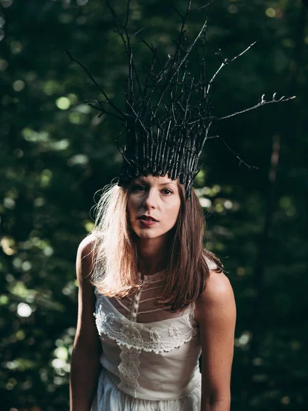 Witch woman with crown standing in forest