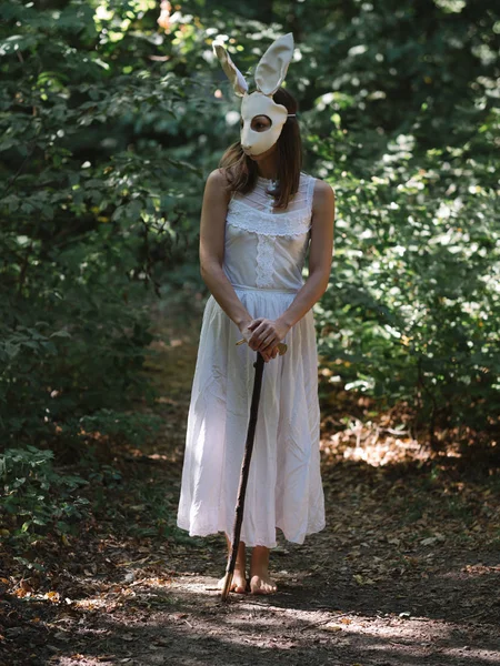 Creepy woman in rabbit mask in forest