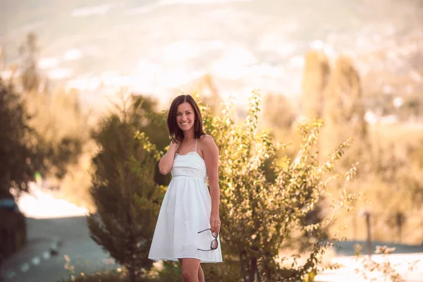 Mujer sonriente en vestido blanco de pie sobre hermoso fondo de crimea —  Fotos de Stock