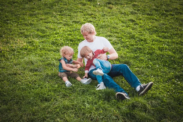 Padre feliz con dos hijos pequeños en el parque —  Fotos de Stock