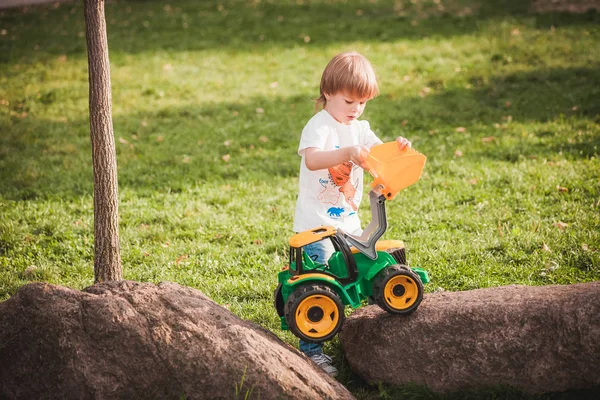 Mignon garçon jouer avec jouet tracteur à jardin — Photo