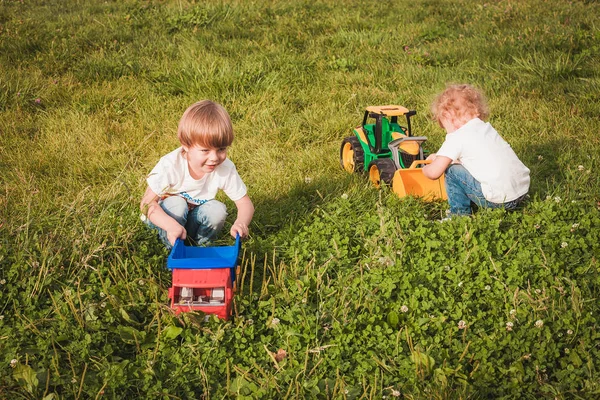 Leuke jongens spelen met Toy tractor in de tuin — Stockfoto