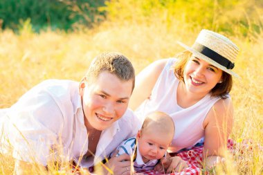 Mutlu bir aile ve küçük bir bebek gün batımında birlikte vakit geçiriyorlar.