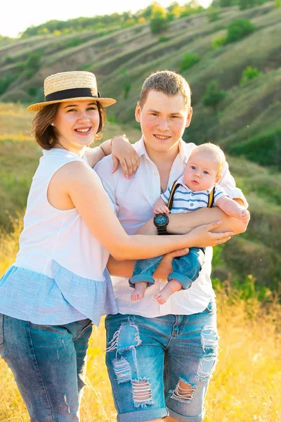 Família feliz com pouco bebê passar o tempo juntos ao pôr do sol — Fotografia de Stock