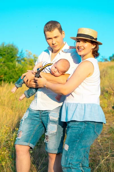 Familia feliz con el pequeño bebé pasando tiempo juntos al atardecer —  Fotos de Stock