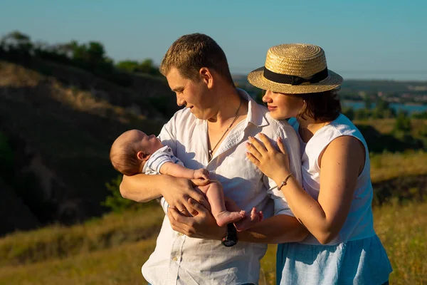 Familia feliz con el pequeño bebé pasando tiempo juntos al atardecer —  Fotos de Stock