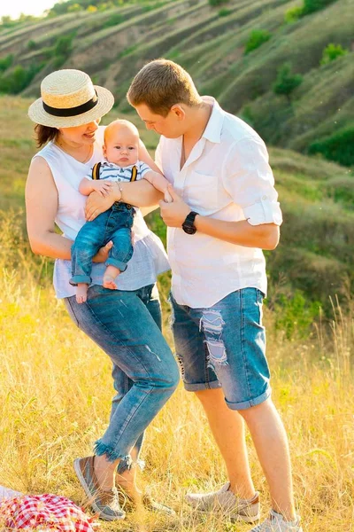 Mutlu bir aile ve küçük bir bebek gün batımında birlikte vakit geçiriyorlar. — Stok fotoğraf