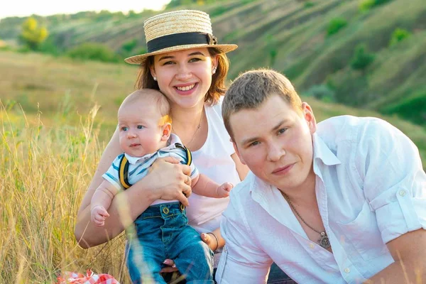 Família feliz com pouco bebê passar o tempo juntos ao pôr do sol — Fotografia de Stock