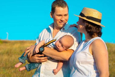 Mutlu bir aile ve küçük bir bebek gün batımında birlikte vakit geçiriyorlar.