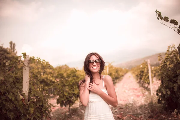 Mulher sorridente de vestido branco em pé na vinha — Fotografia de Stock