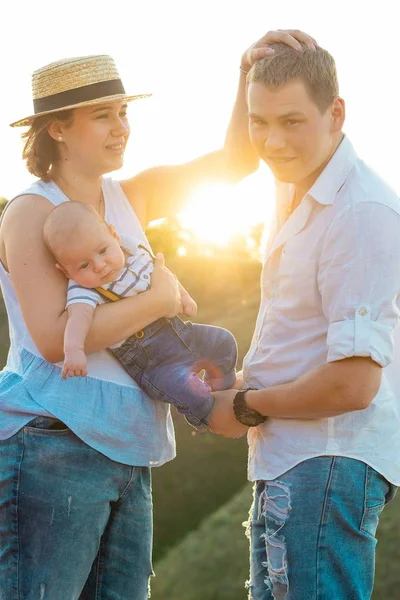 Família feliz com pouco bebê passar o tempo juntos ao pôr do sol — Fotografia de Stock