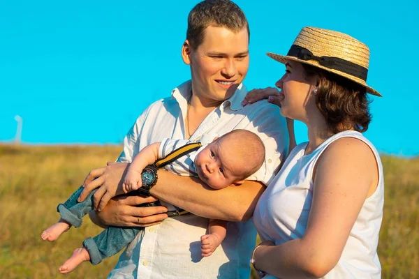 Ευτυχισμένη οικογένεια με το μωρό να περνάει χρόνο μαζί το ηλιοβασίλεμα. — Φωτογραφία Αρχείου