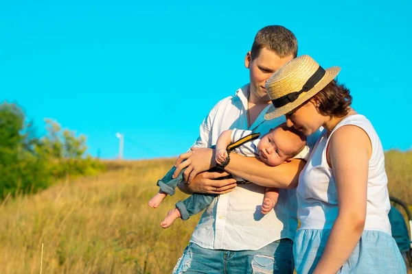 Familia feliz con el pequeño bebé pasando tiempo juntos al atardecer —  Fotos de Stock