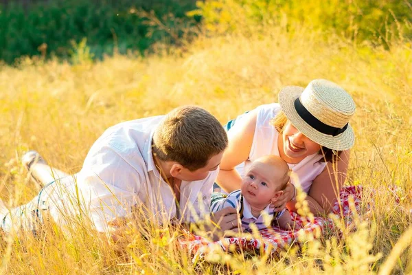 Familie mit Baby bei Sonnenuntergang im Sommer. — Stockfoto