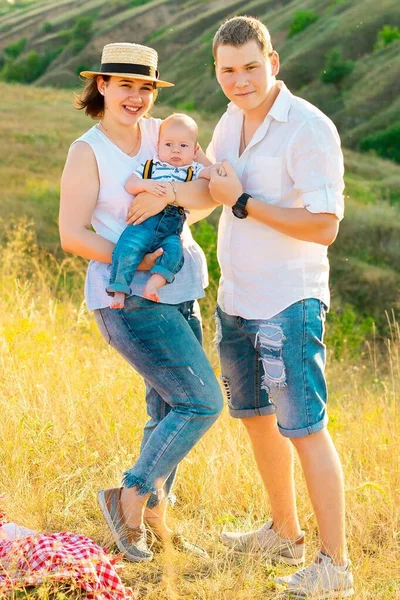 Familia feliz con el pequeño bebé pasando tiempo juntos al atardecer —  Fotos de Stock