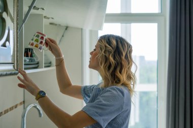 Kadın bardağı rafa koydu.