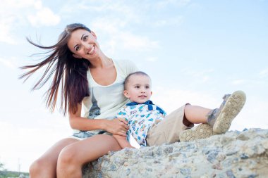 2 yaşındaki oğlu deniz kenarında tatilde olan mutlu bir anne.