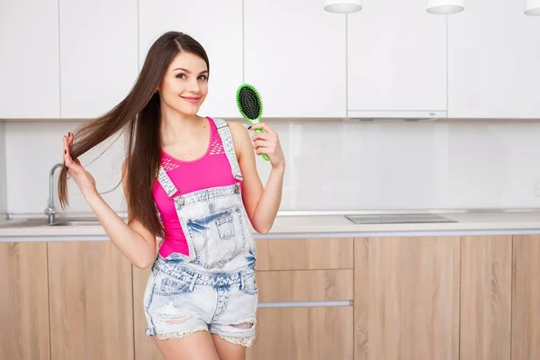 Menina de pé na cozinha e pentear o cabelo — Fotografia de Stock