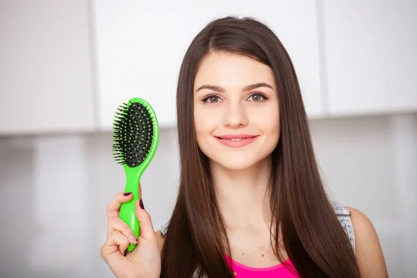 Menina segura uma escova de cabelo sem cabelo e sorrindo — Fotografia de Stock