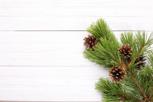 Kerstversiering Vergulde Kegels Een Pine Tak Een Witte Houten Achtergrond — Stockfoto