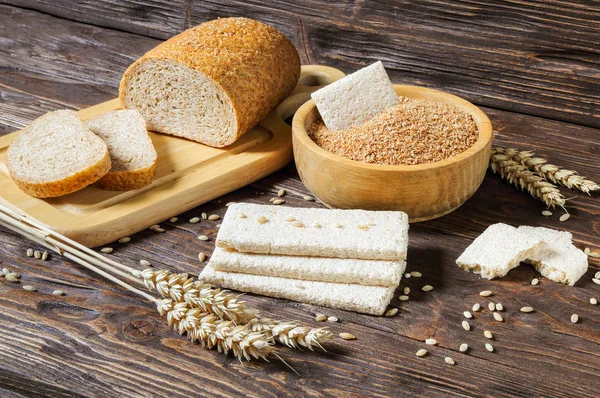 Wheat bran, bran bread and dry biscuits on a wooden table