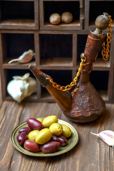 Olijven in een bronzen platel op een houten keukentafel — Stockfoto