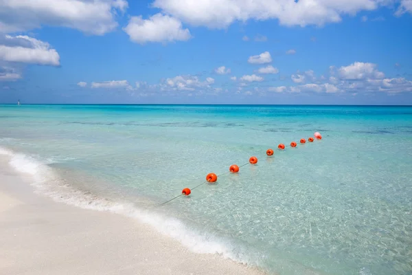 Chain of orange buoys against the blue sea and white beach sand — Stock Photo, Image