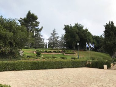 Kudüs - 9 Mayıs 2018: Yedi Kollu Şamdan ve Mount Herzl Ulusal Mezarlığı'ndaki bahçeler. 