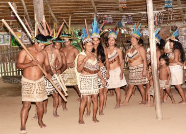 IQUITOS, PERU - OCTOBER 18, 2015: Bora community of Peru performing traditional dance. The tribe relocated from Ecuador dance in a traditional community hut. clipart