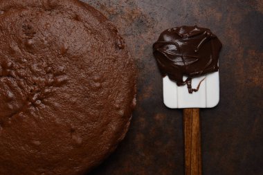 Düz yatıyordu closeup bir spatula ve buzlanma bir topak unfrosted bir çikolatalı kek.