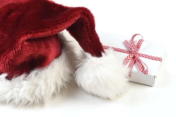 特写镜头的圣诞老人帽子在白色与一个小包裹的礼物 — 图库照片