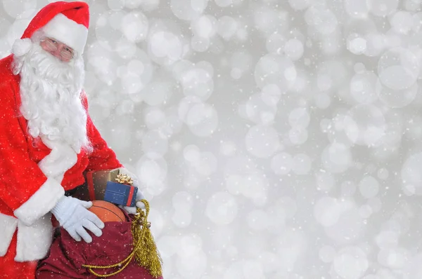 Närbild av jultomte med sin påse med leksaker över en silver bokeh — Stockfoto