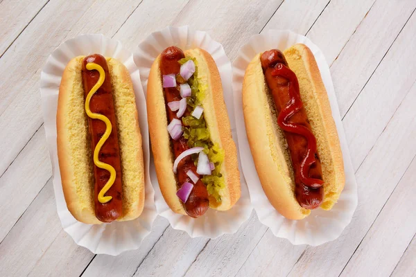 Vista Superiore Tre Hot Dog Tavolo Legno Con Diversi Condimenti — Foto Stock