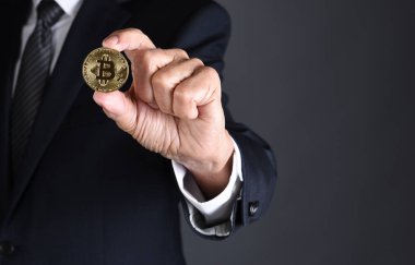 Bir Businessmanholding bir Bitcoin parmaklarını içinde closeup. Yalnızca gövde, adam kopya alanı ile tanınmaz.