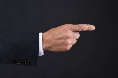Closeup bir el işaret mans. Koyu gri arka plan üzerinde koyu takım elbise.