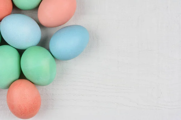 Pastell gefärbte Eier auf einem weißen Holztisch mit Textfreiraum. — Stockfoto