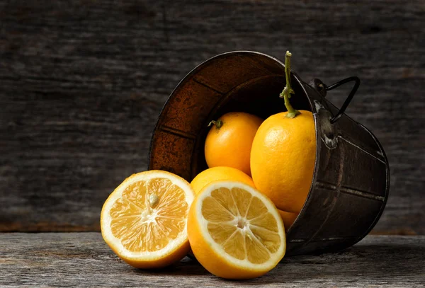 素朴な木製の表面上にこぼれる新鮮な摘みレモンとの側でバケツのクローズ アップ — ストック写真