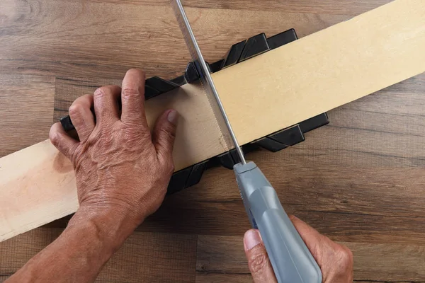 Alto angolo di primo piano di un falegname utilizzando una scatola mitra e mano sa — Foto Stock